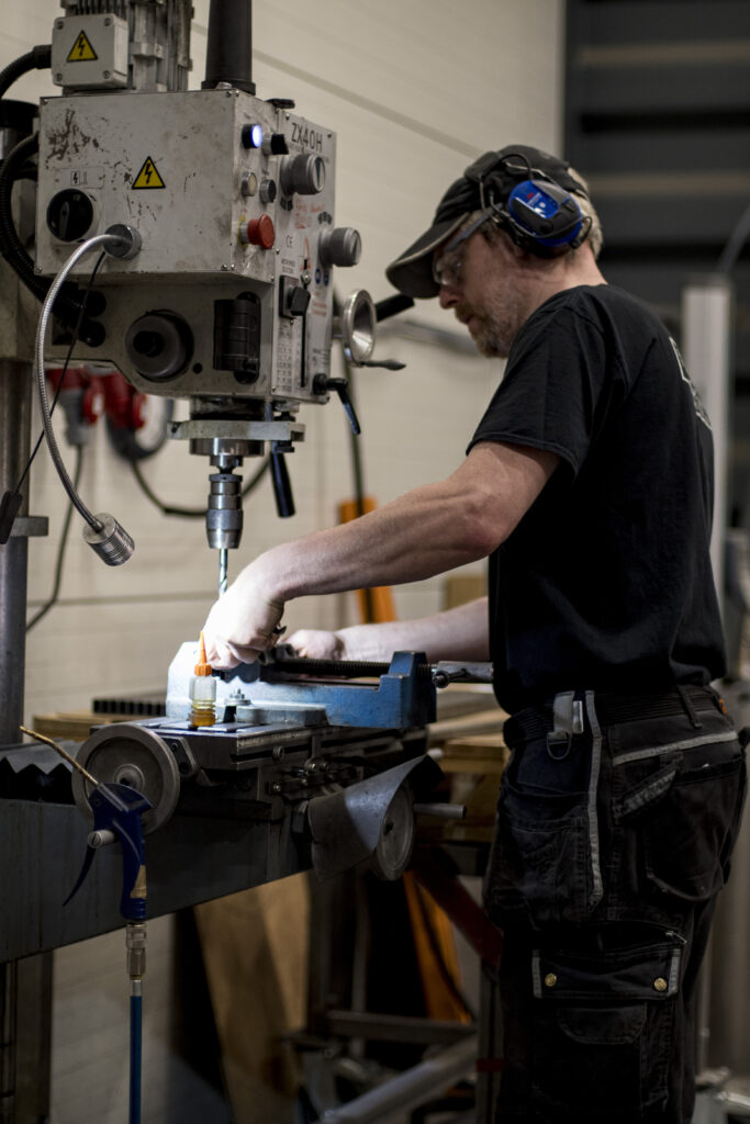 bild (9) Person som står i en skärande bearbetningsmaskin och bearbetar en produkt