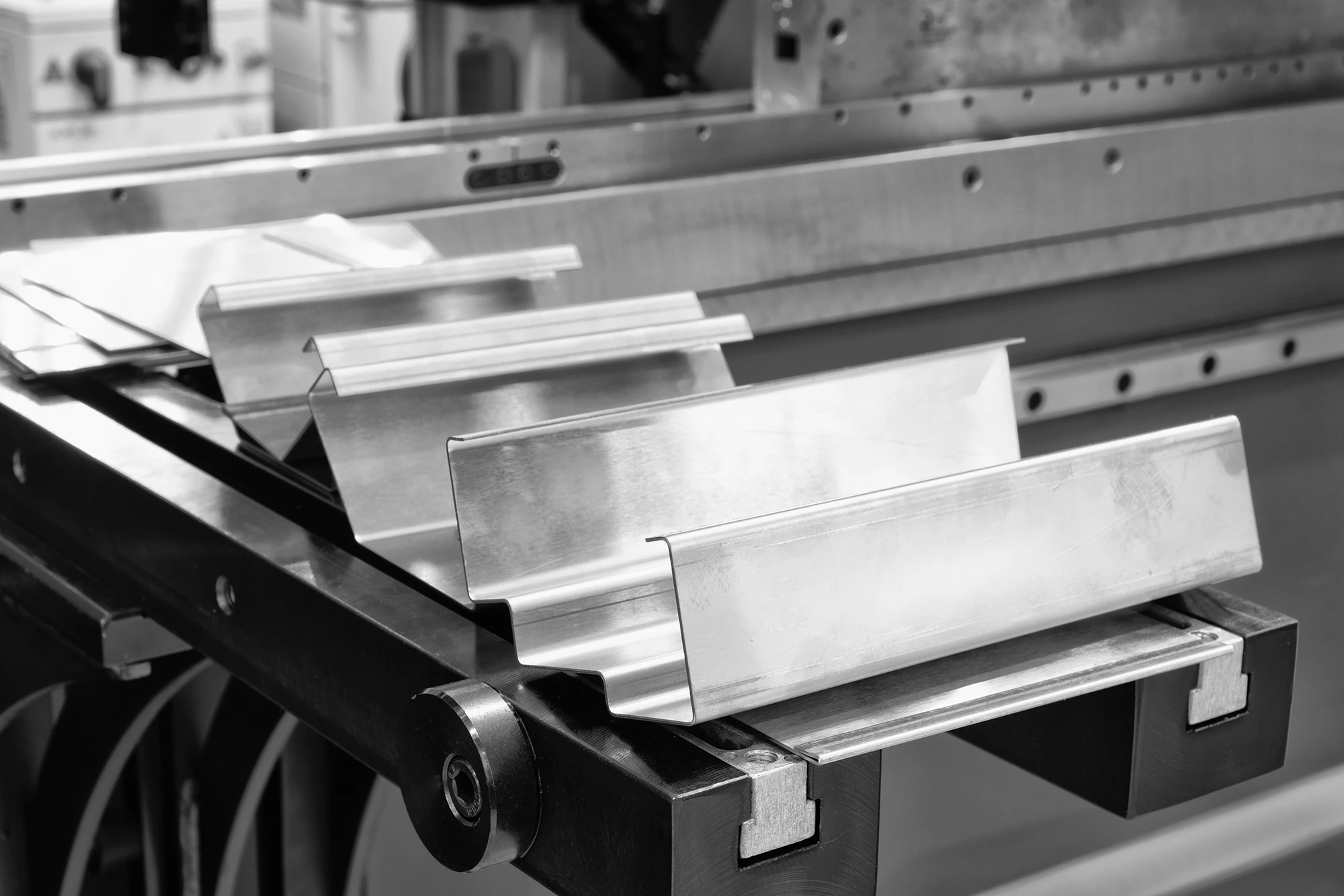 Silverfärgad Kantpressningsmaskin i arbete, som böjt metallplåt.