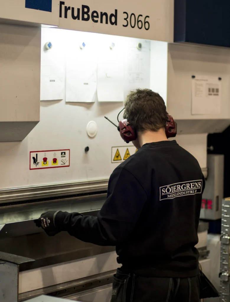 tjanster Verkstadsarbetare som står framför en maskin med ryggen mot kameran